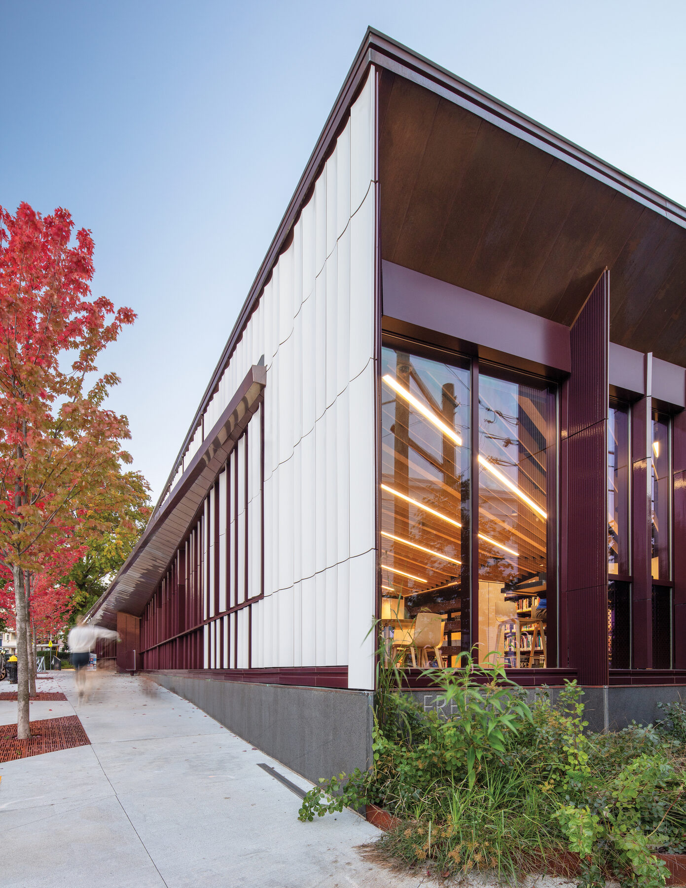 Adams Street Branch Library at twilight, with white standing seam roof terminating at terracotta wall