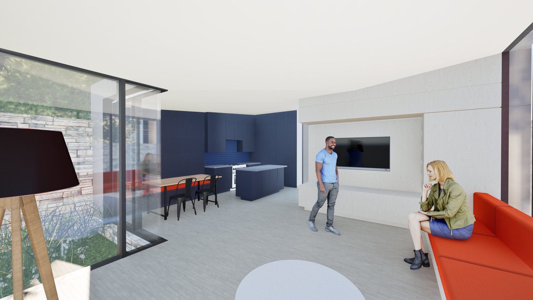 Interior view of the great room looking toward the kitchen, with a glazed wall at left opening to a stone-walled courtyard planted with grasses, a dining table at the courtyard edge, and a red banquette at right