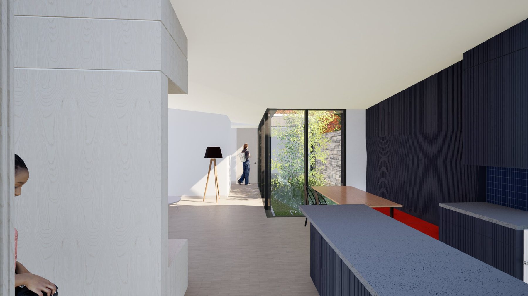 View from the entry looking along the length of the plan, with a tall glazed slot opening to a courtyard in the middle distance and a figure standing in the light