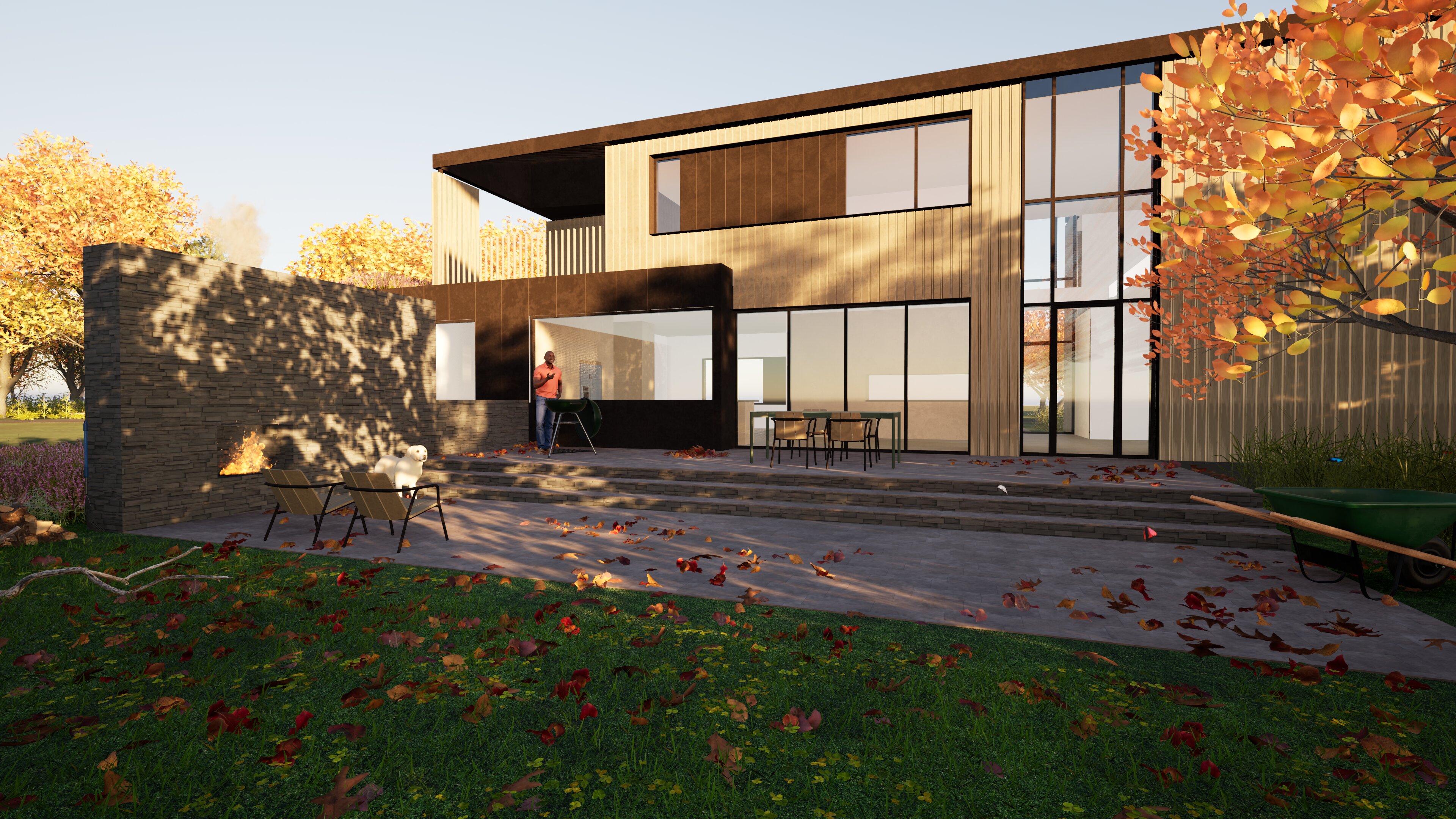 Rear view of the renovated house in late afternoon light: a broad terrace of stone pavers stepping down to a lawn, full-height glazing on the ground floor opening to the kitchen and dining, an upper exterior terrace carved into the second-floor volume above, a stone garden wall with a built-in fireplace at left, and autumn leaves across the grass